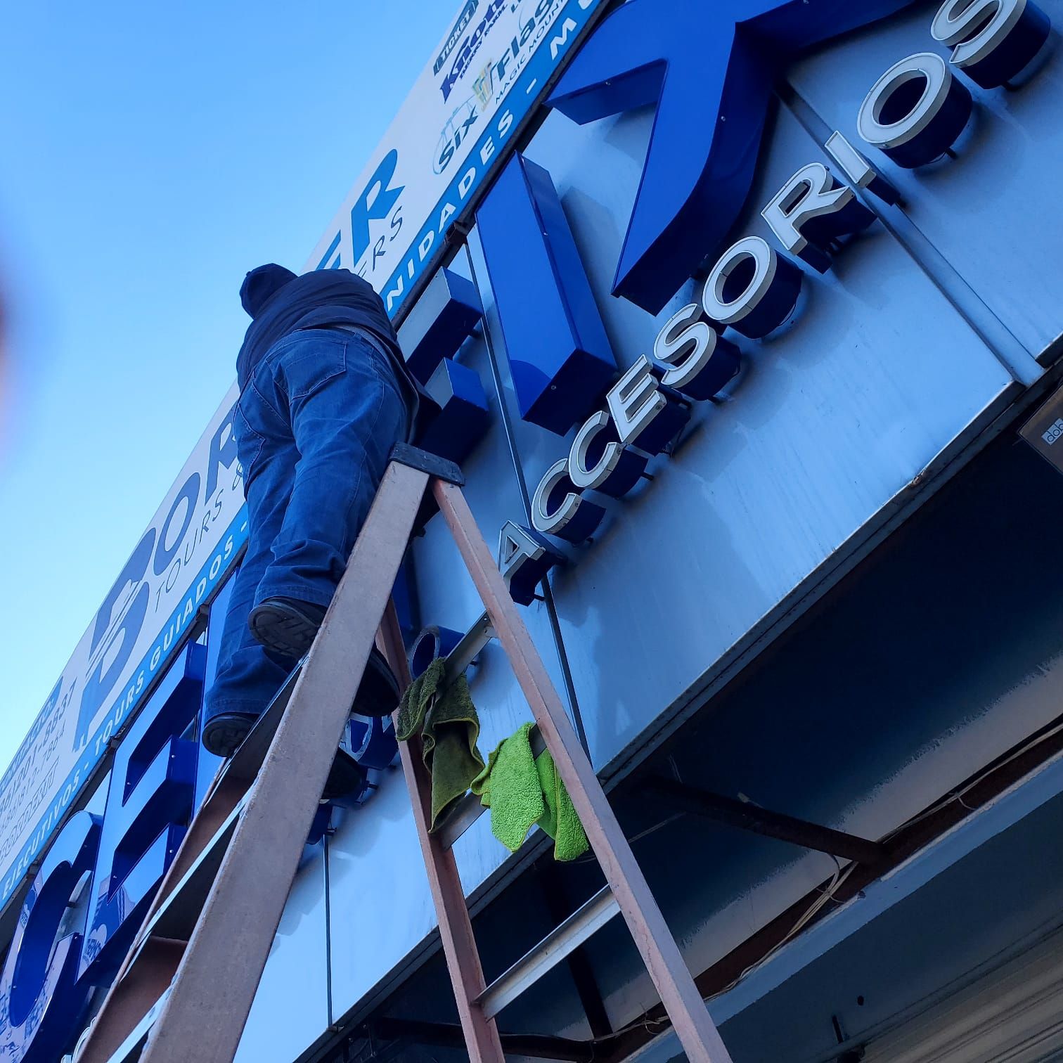Limpieza: el técnico trabaja desde la escalera sobre las letras con dos microfibras a la mano.
