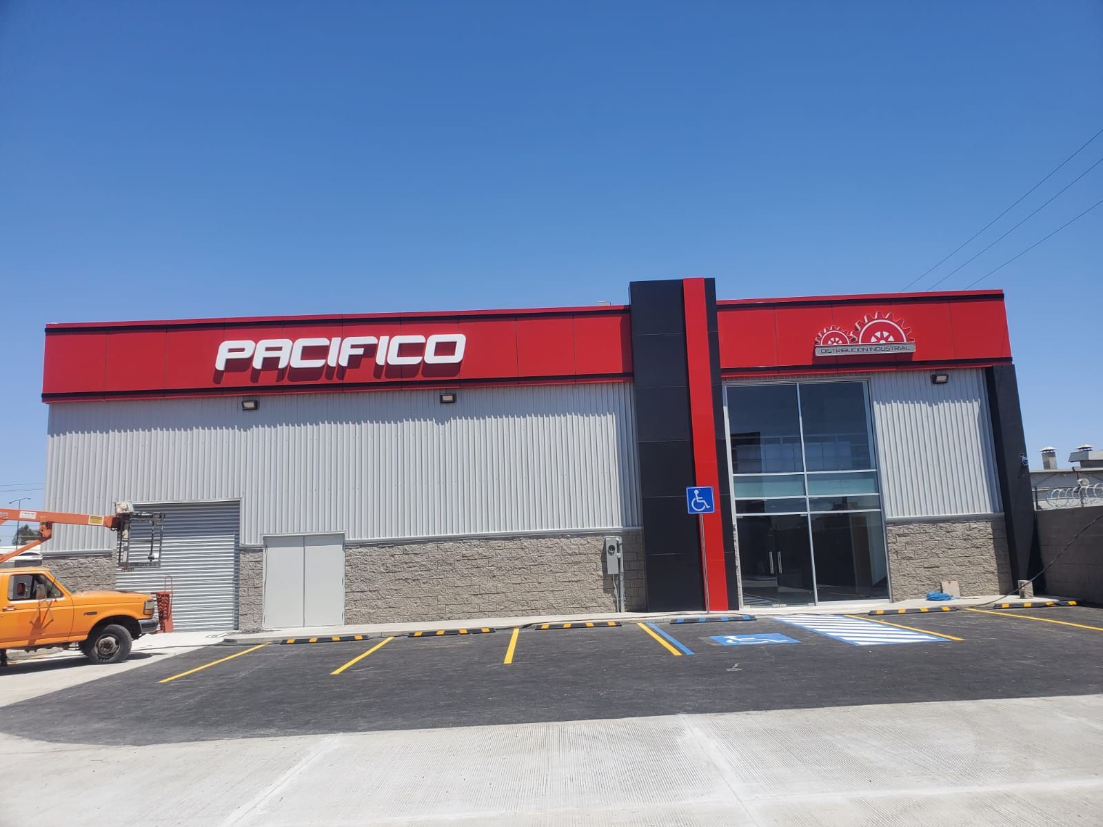 Fachada de Pacífico Distribución Industrial en panel de aluminio rojo y negro, con las letras corpóreas blancas ya montadas.