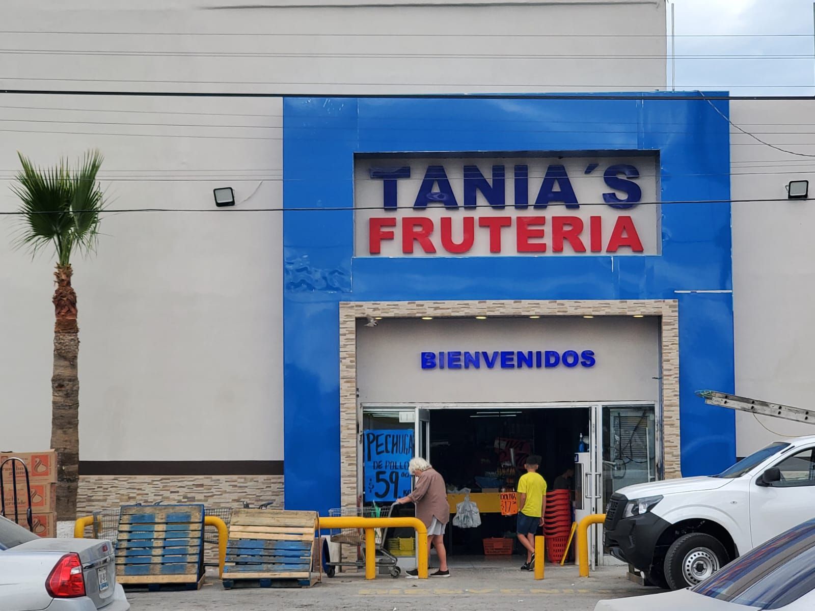 Las mismas letras de Tania's Frutería ya instaladas sobre la fachada azul del local, con la tienda abierta al público.